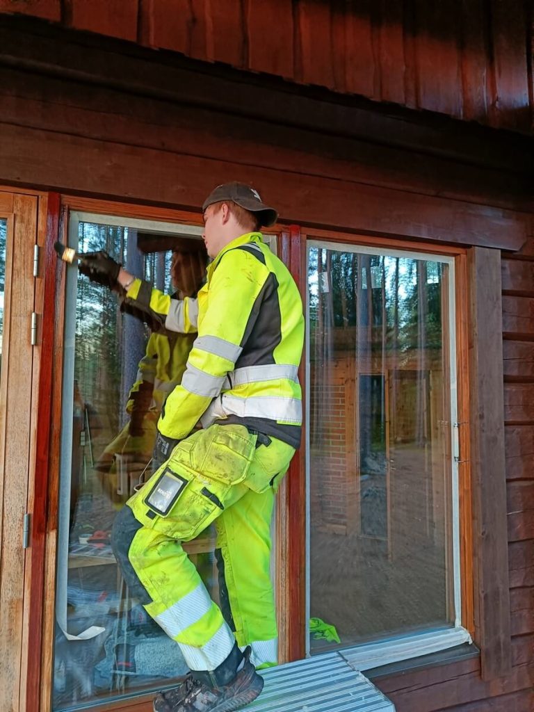 Renoxin työntekijä maalaamassa hirsihuvilan ikkunan pokia Somerolla.