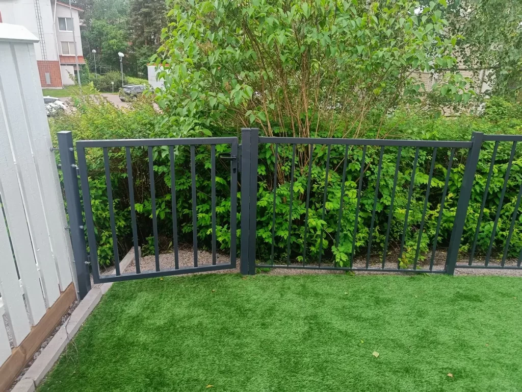 Musta teräsaita ja puutarhaportti asennettuna rivitalon takapihalle Naantalissa.