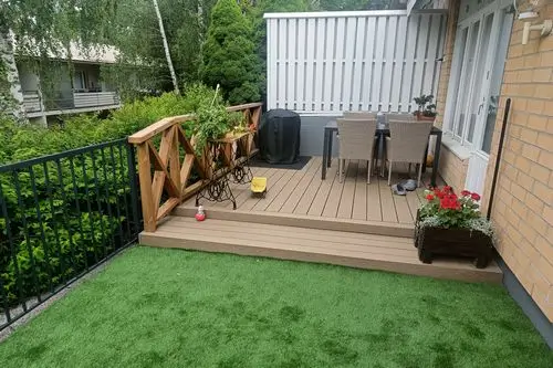 Uusi komposiittinen terassi Raisiossa rivitalon takapihalla. Vihreä tekonurmi, joka on juuri asennettu.